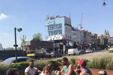 People sitting at pub table with Kentish Town mural in the background